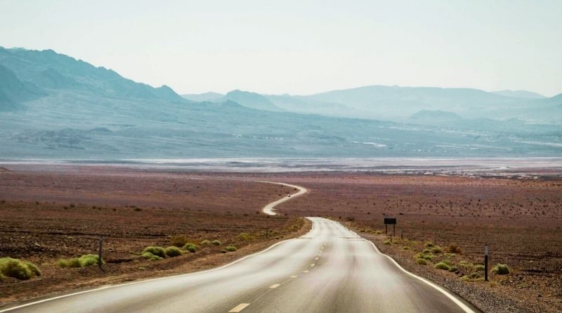 Empty road continues far into the distance of Death Valley landscape