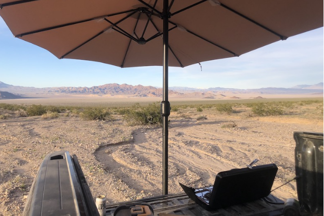 Looking at desert landscape from back of truck bed while covered by Humbra mobile shade solution